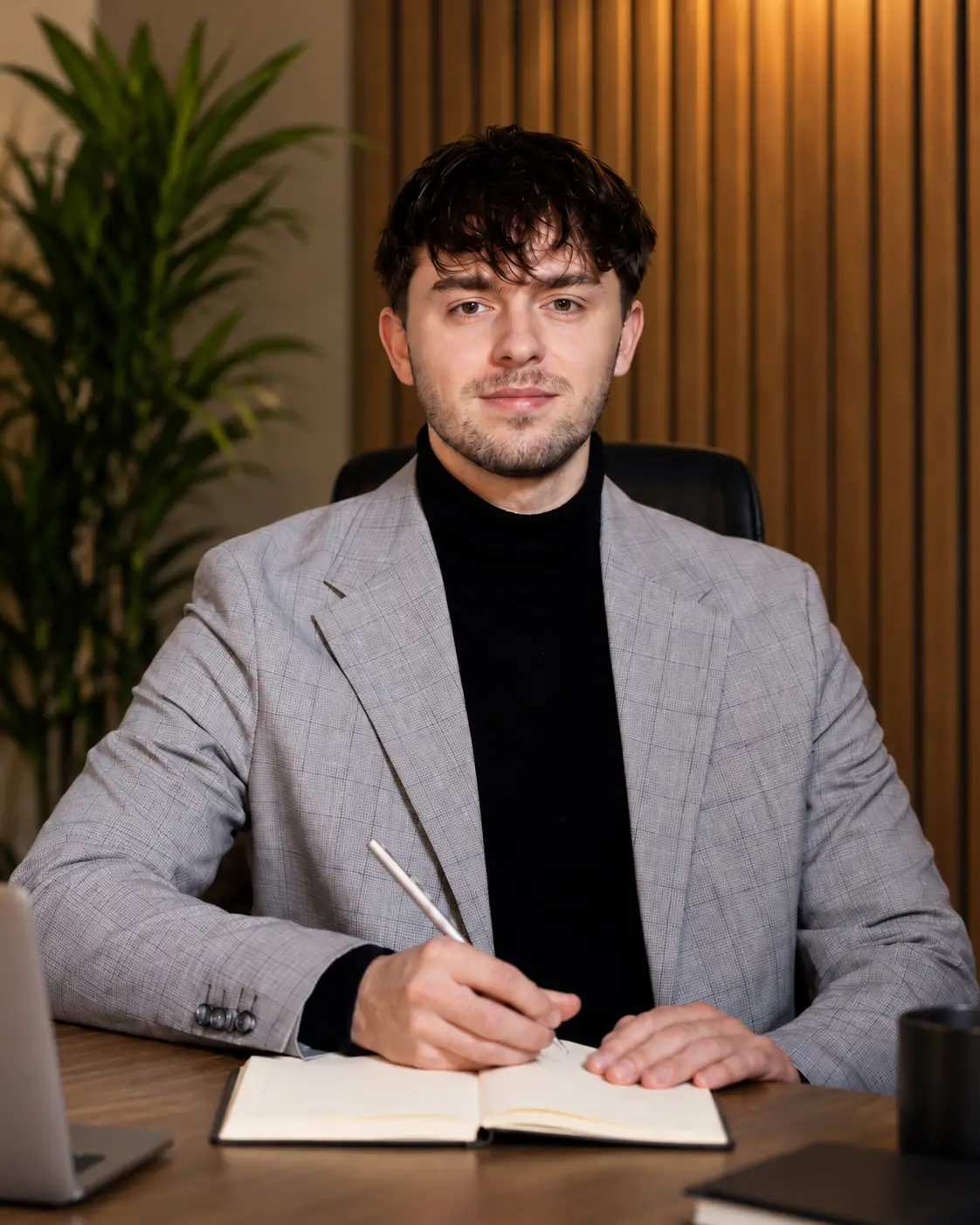 Jakub Brochocki przy biurku z laptopem i notesem
